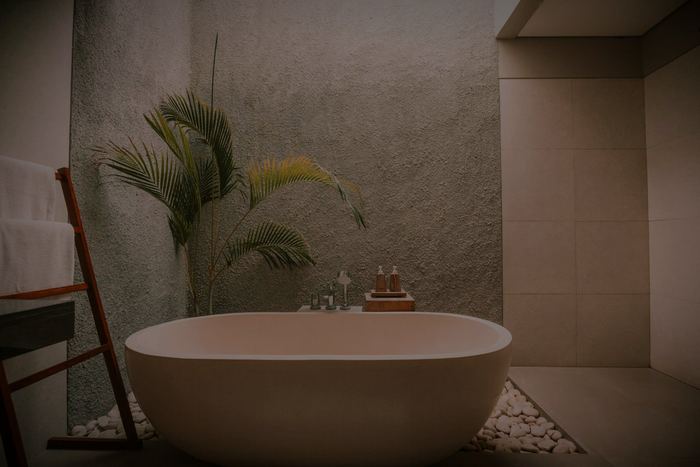 A stone bath in a treatment pavilion, a palm in the corner and a bed of white pebbles.