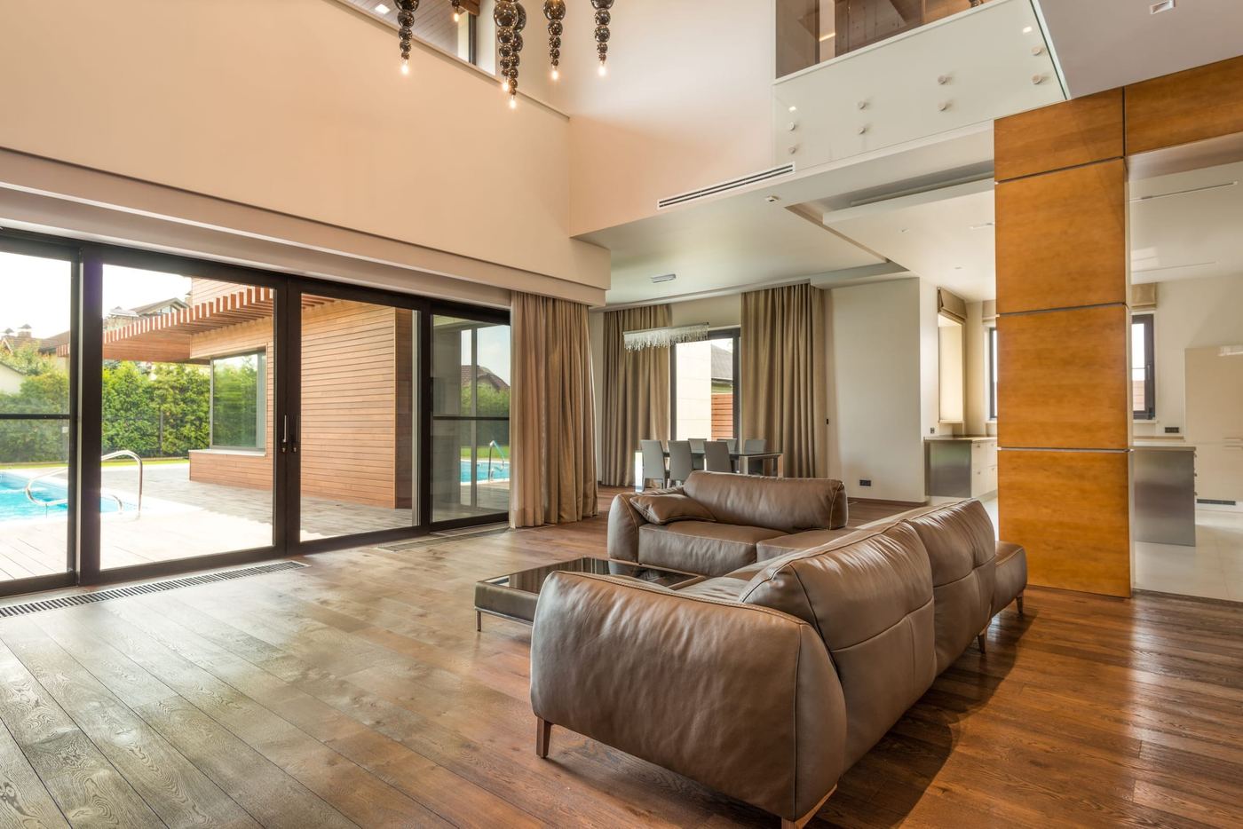 A double height living room with leather sofas and glass doors open to the pool.