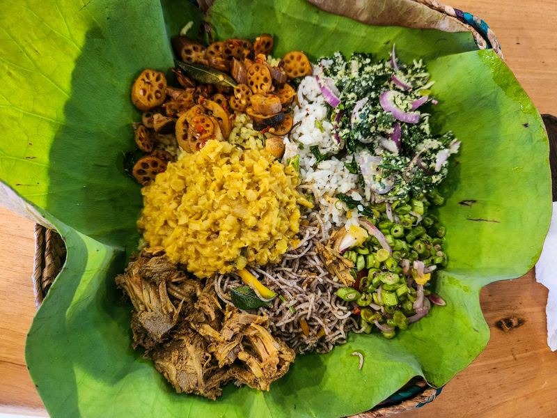 Rice and curry served on a lotus leaf: dhal, greens, sambol and fried lotus root.