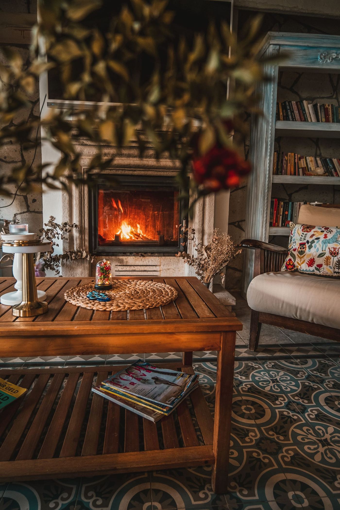 A fire lit in the sitting room fireplace, a low table and an armchair before it.