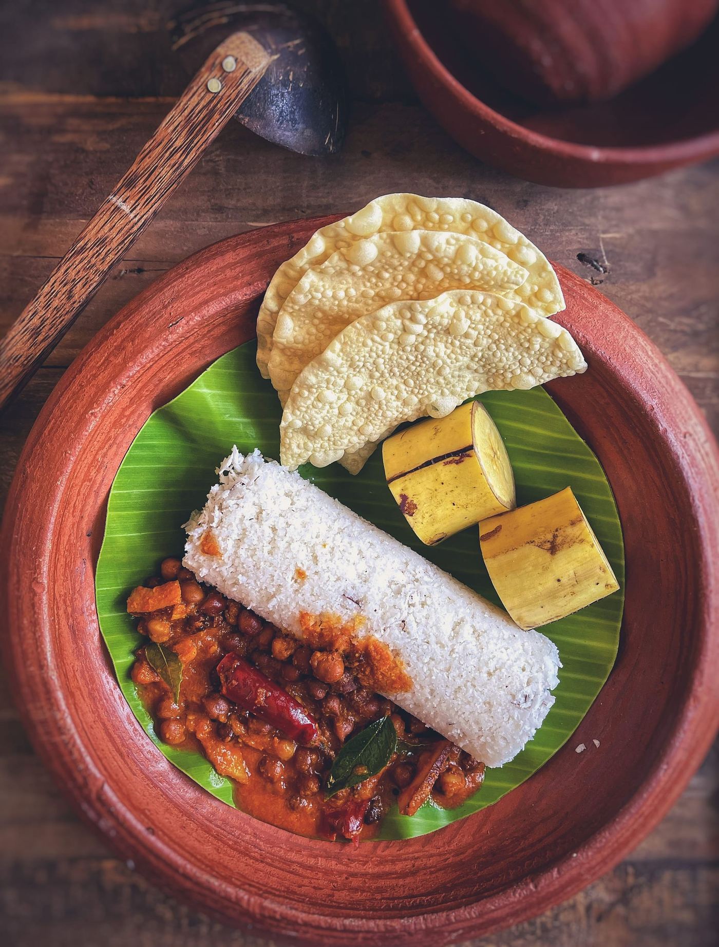 Breakfast on a banana leaf: a steamed rice cake, curry, banana and poppadoms.
