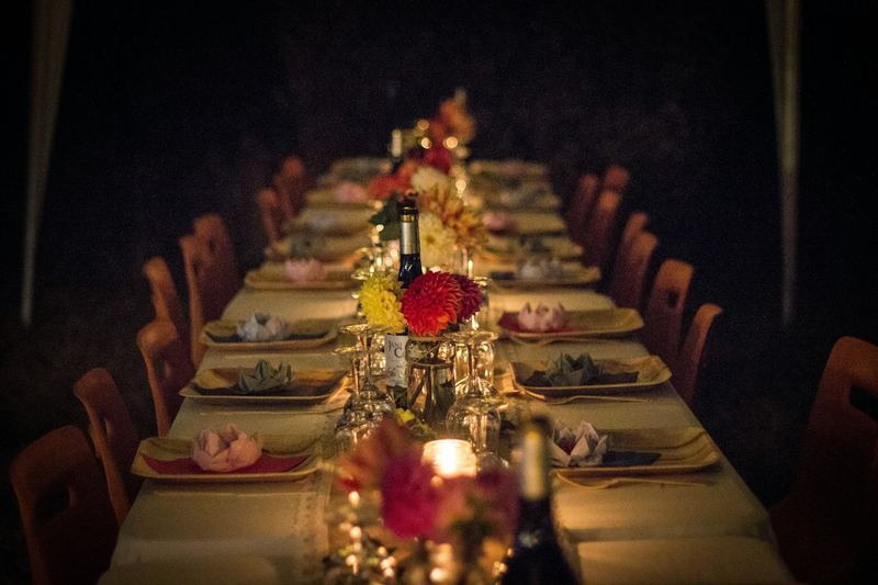 A long candlelit dinner table laid with flowers in a dark room.
