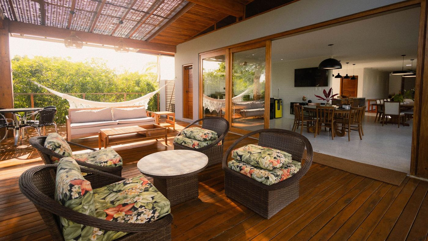 An open sided living room with patterned wicker armchairs, a dining table beyond and the garden outside.