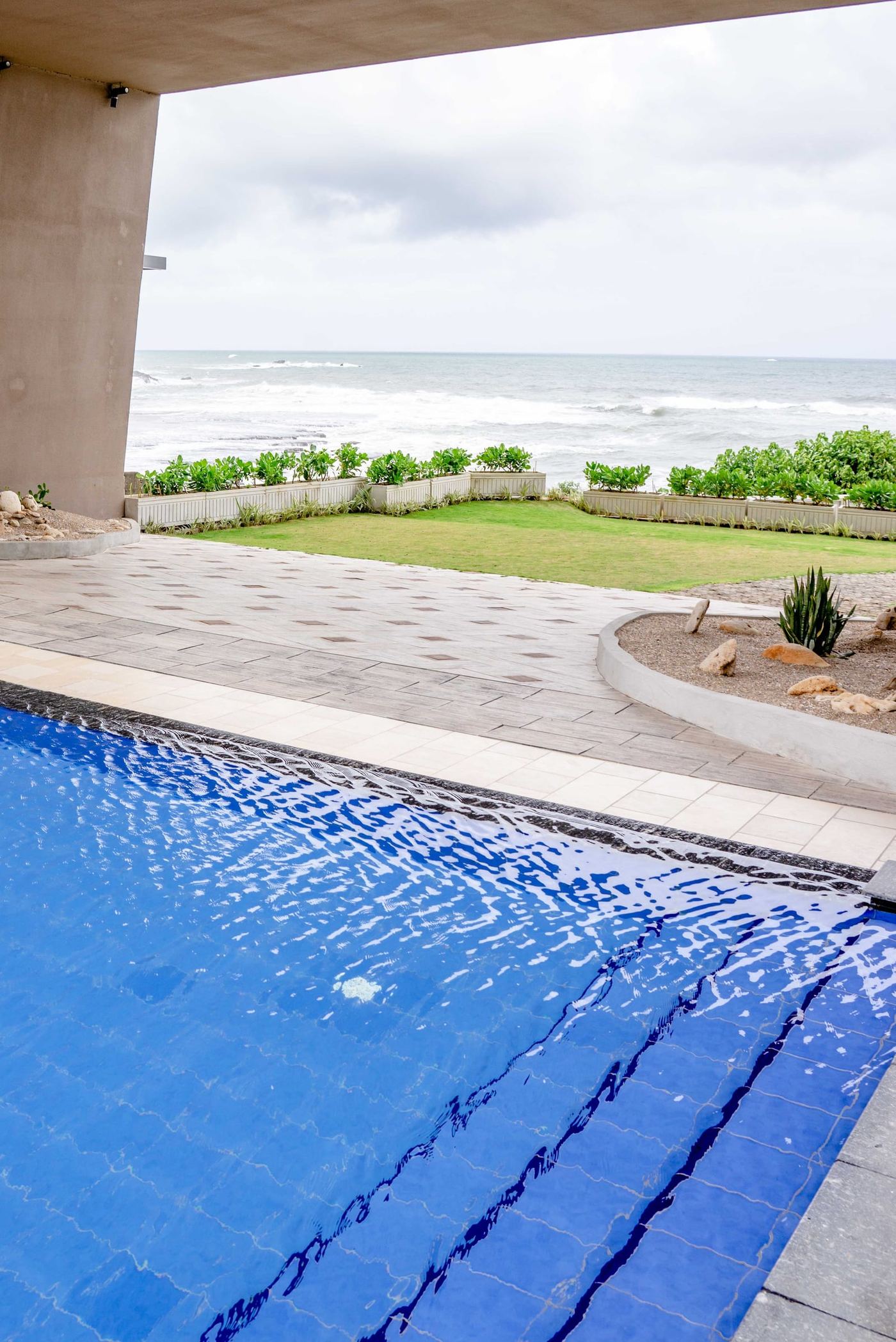 The pool's edge on a lawn, with the sea beyond the garden wall.