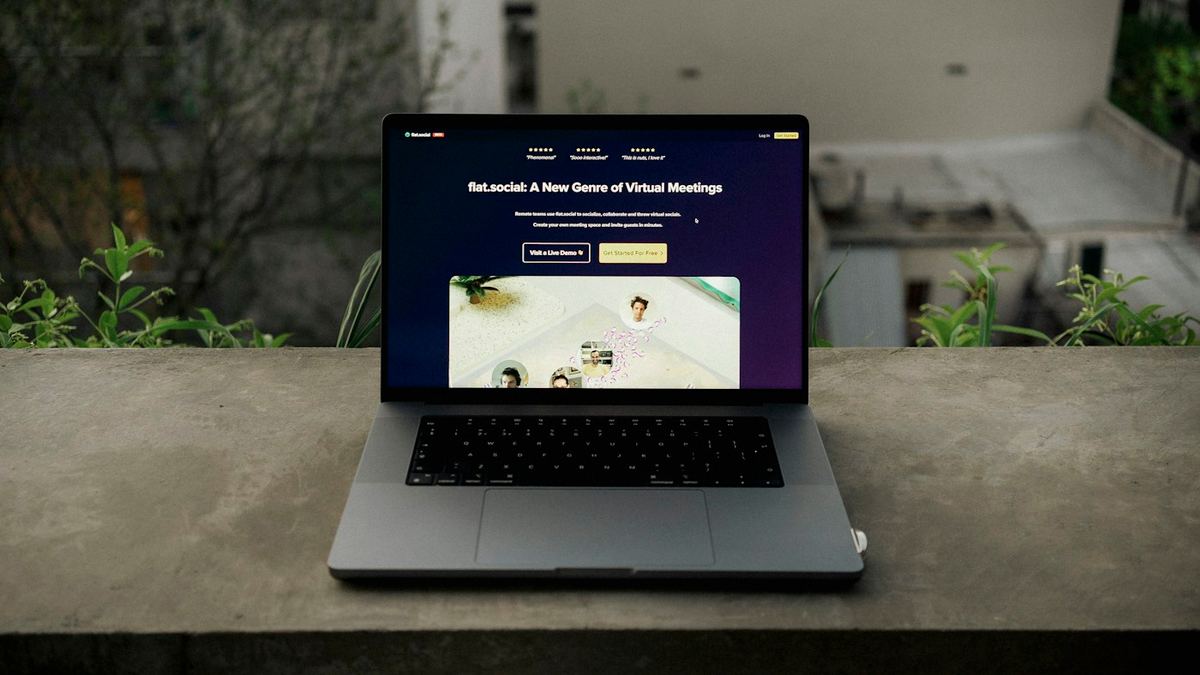 A laptop on a concrete ledge among plants, a website open on its screen.